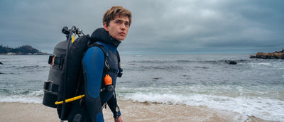 Austin Abrams as diver Jay Gardiner on a California beach in the 2026 film Whalefall; 20th Century Studios promotional still